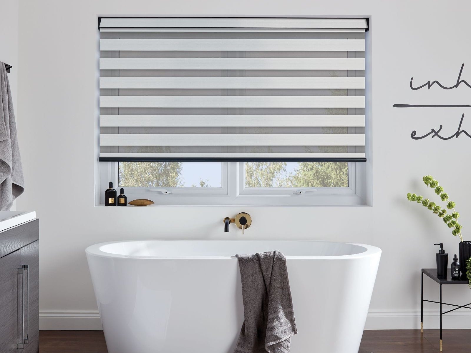 Made-to-measure Day and Night blind installed in a contemporary Essex bathroom with a white freestanding bath and neutral décor.