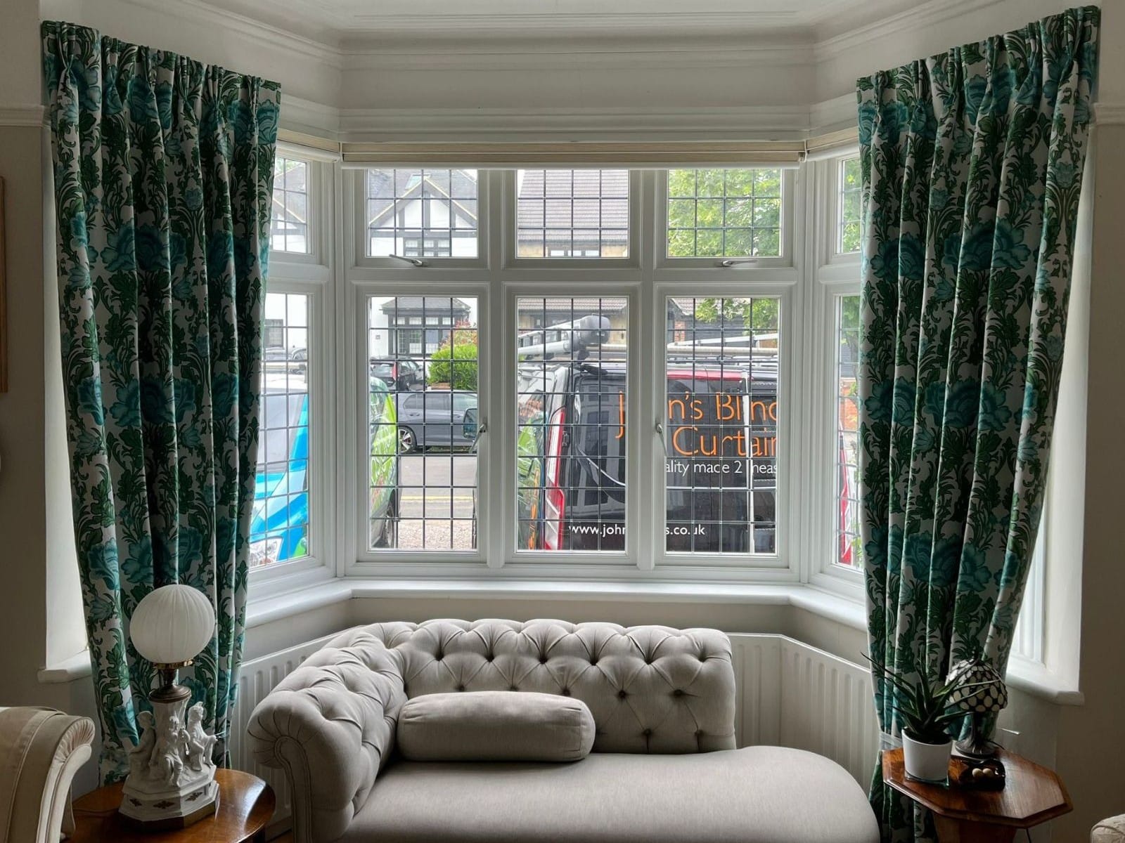 Triple pinch pleat curtains in patterned fabric, fitted to a bay window in an Essex living room.