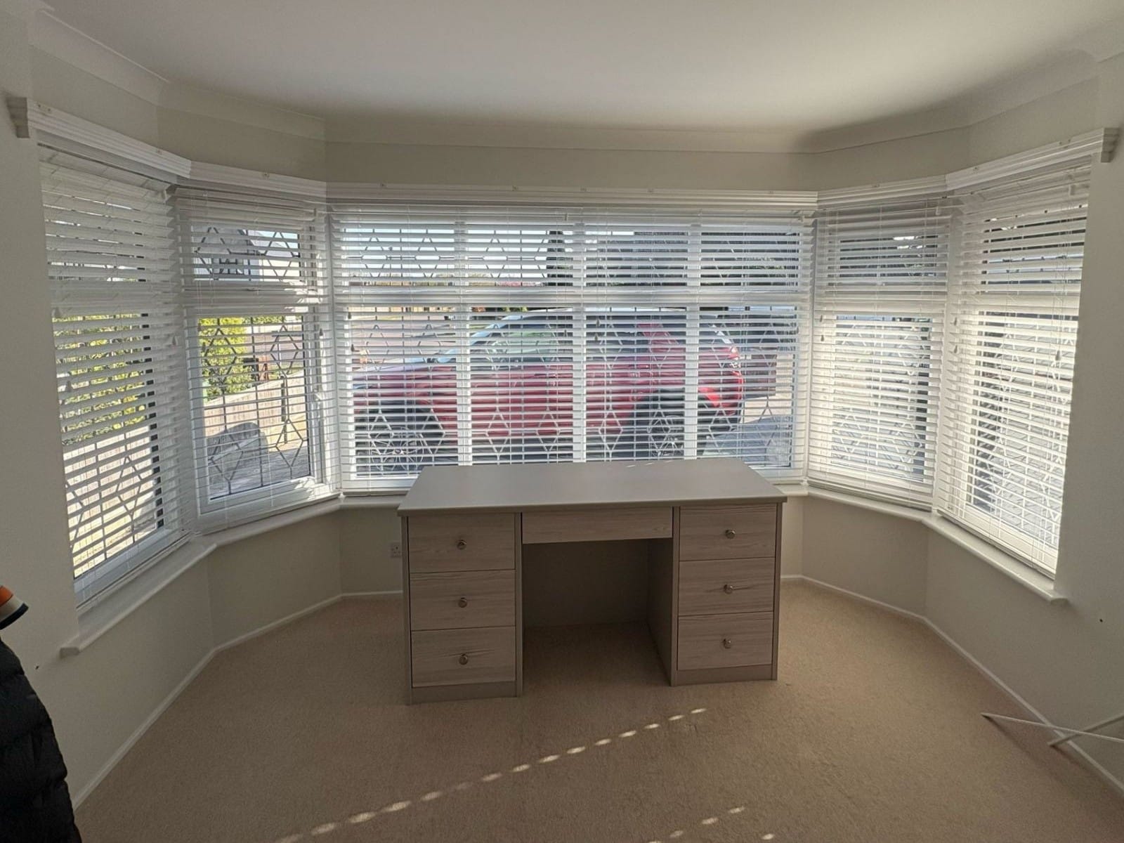 Made-to-measure white faux wood Venetian blinds installed in a large bay window of an Essex home office, offering privacy and light control.