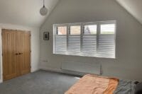 White plantation shutters fitted in a bright modern bedroom in Essex, offering privacy and light control – John’s Blinds & Curtains.