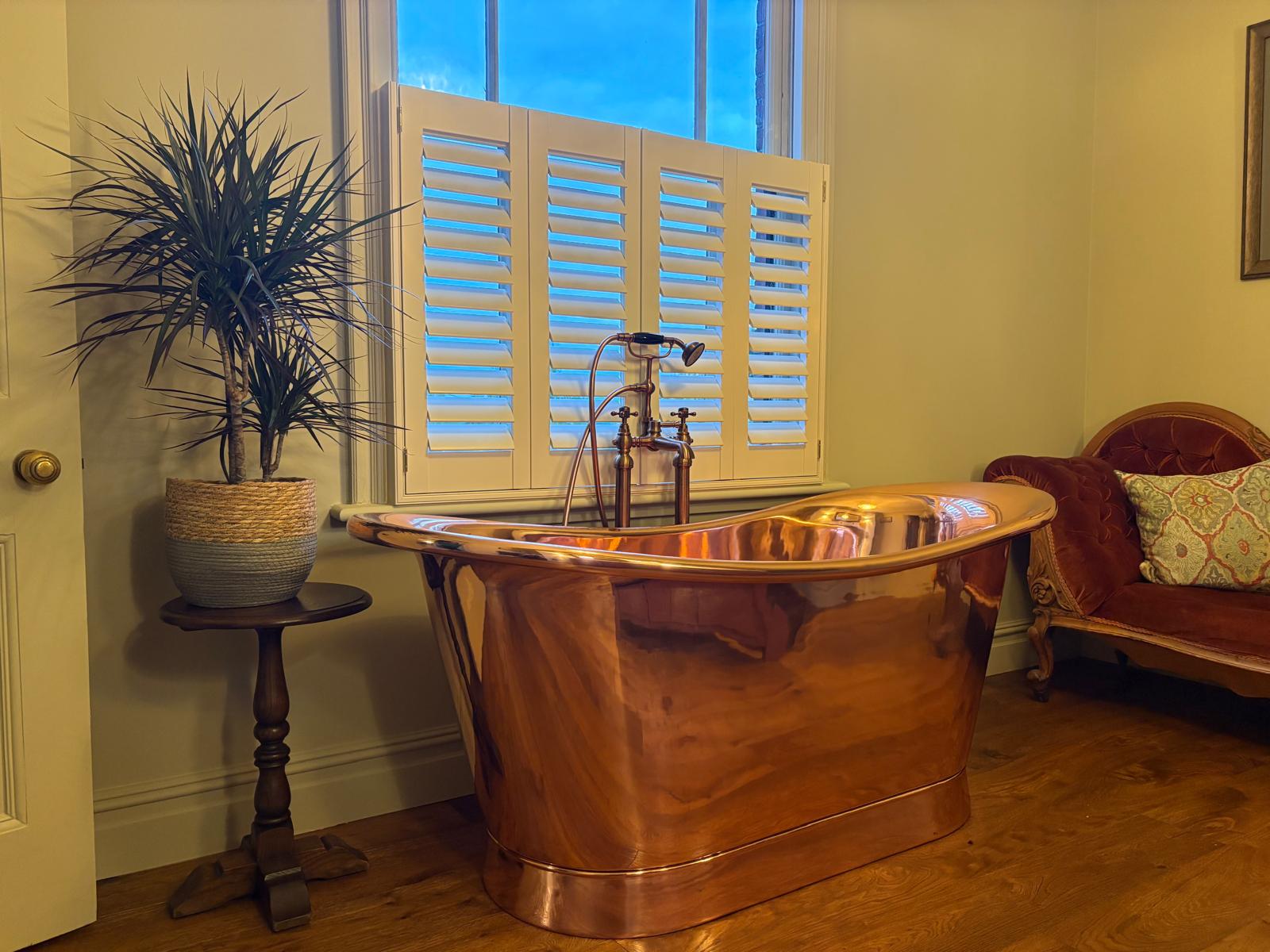 Café-style white shutters fitted in a traditional bathroom by John’s Blinds & Curtains in Essex.