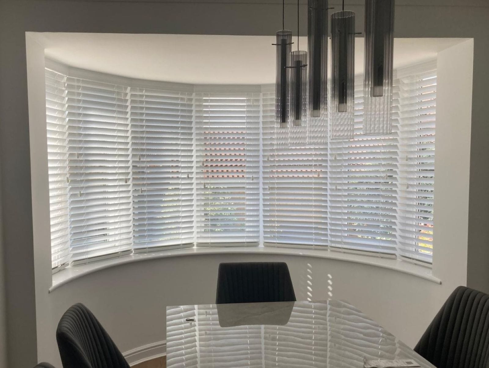 White Venetian blinds fitted to a curved bay window by John’s Blinds & Curtains in Essex.