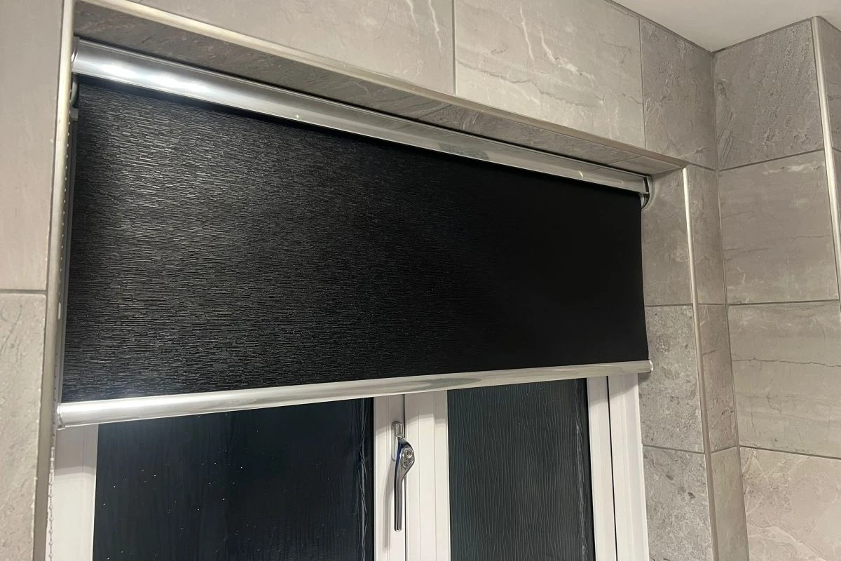 Black moisture-resistant cassette roller blind fitted above a bathroom window, designed for privacy and humid environments.