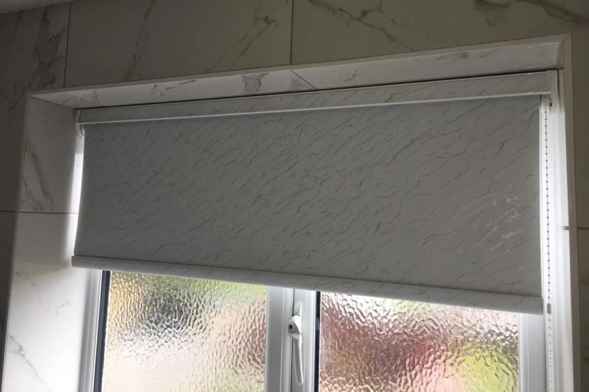 Silver & Grey moisture-resistant PVC roller blind fitted above a bathroom window with frosted glass, ideal for privacy and humid environments.