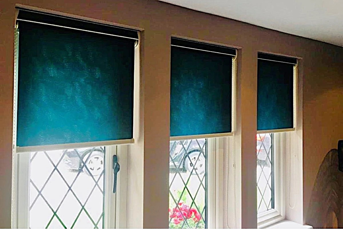 Cassette roller blinds fitted above three leaded windows in an older-style home, providing clean, modern shading.