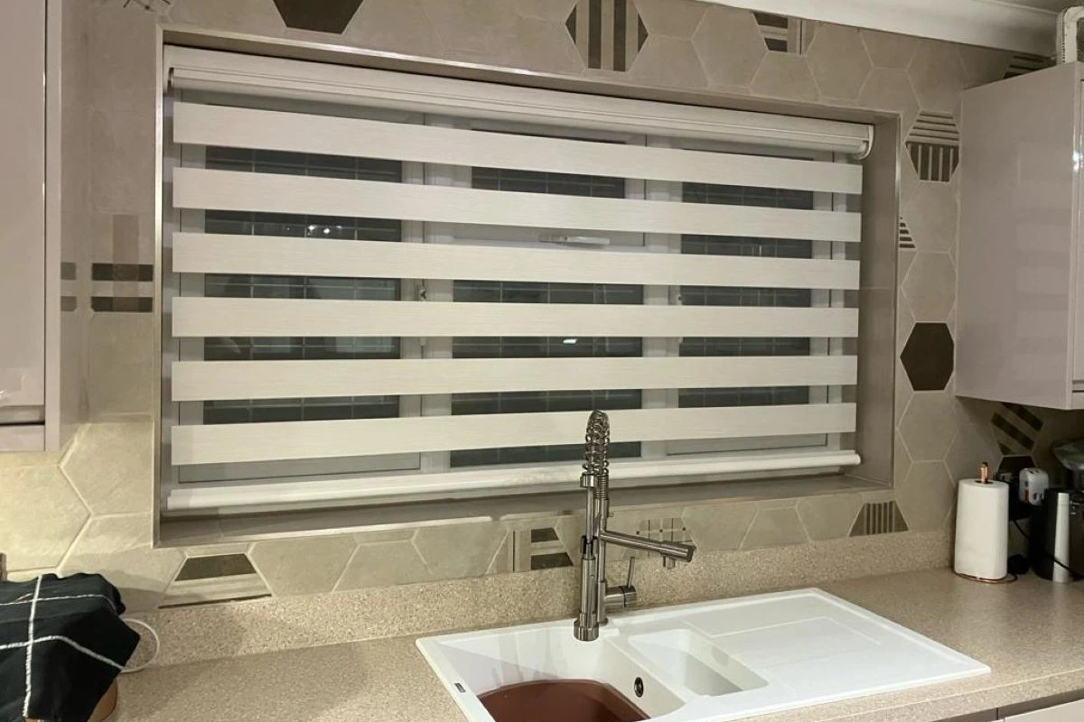 Day and Night Vision blind fitted above a kitchen sink window with alternating sheer and solid stripes