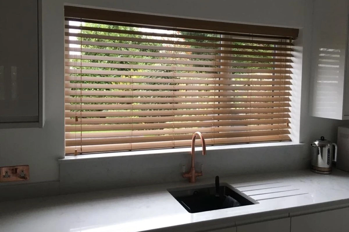 Faux Wood Venetian Blind in Kitchen Sink Window Faux wood Venetian blind fitted above a kitchen sink window with a wood-effect finish
