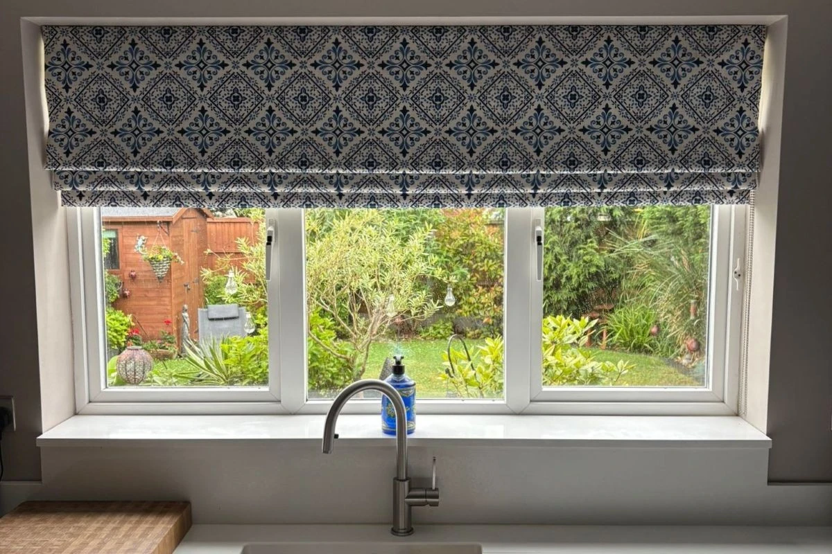 Patterned Roman blind fitted above a kitchen sink window in a modern kitchen