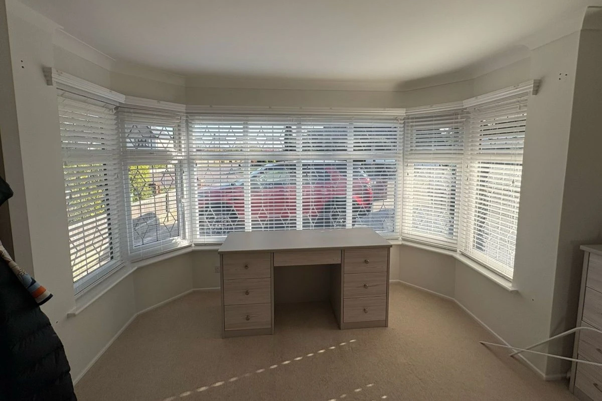 White Faux Wood Venetian Blinds in Large Bay Window White faux wood Venetian blinds fitted across a large bay window in a bedroom or dressing room.