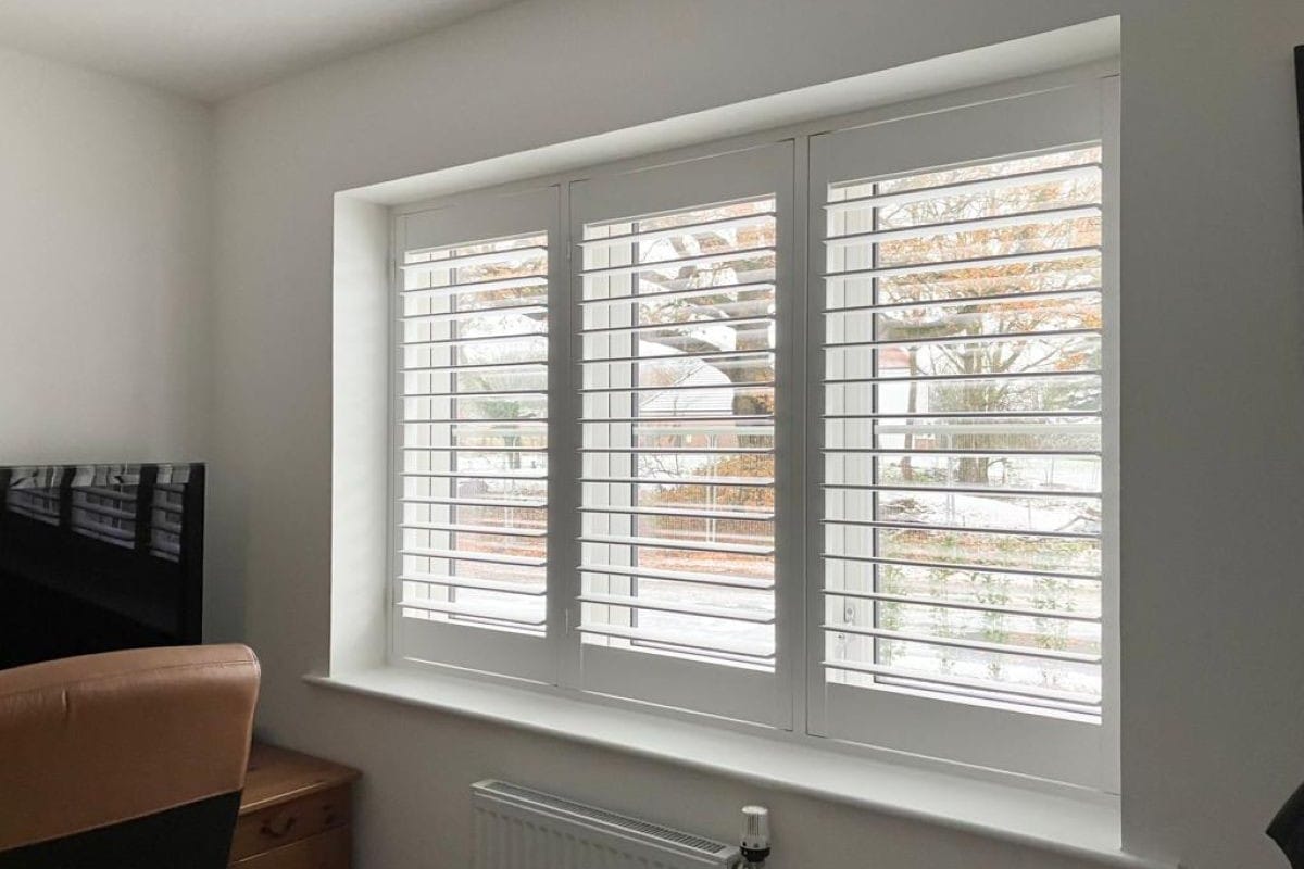 White plantation shutters providing adjustable light control in a home office