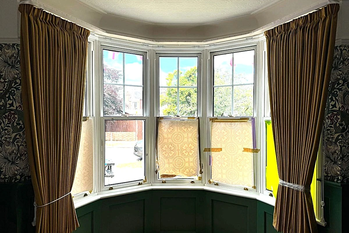 Monument ochre curtains fitted to a bay window with tiebacks and a curved curtain track in a period home