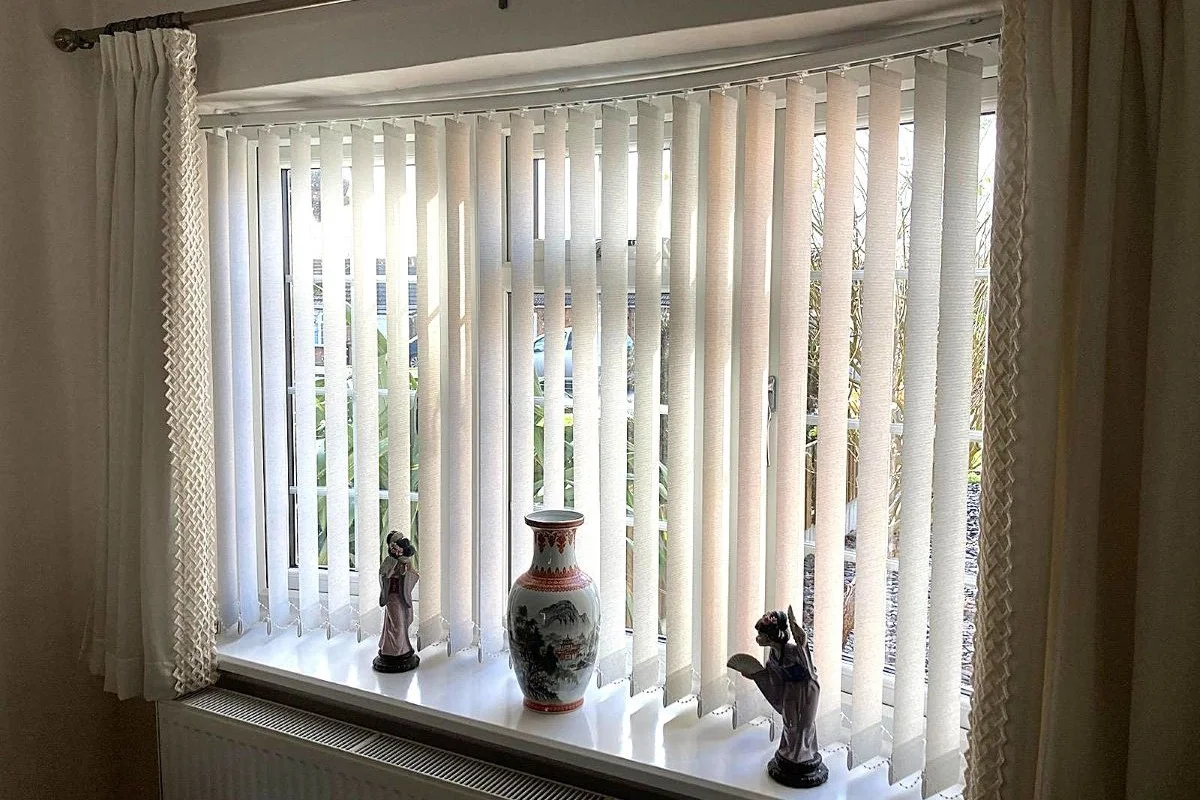 Curved bay window fitted with vertical blinds in Ennis Arran fabric, providing soft light filtering and privacy in a living room