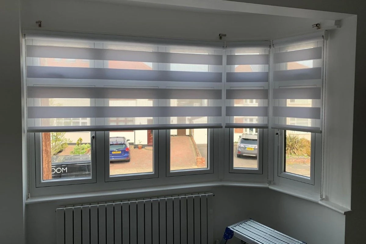 Day and night blinds fitted across a bay window, allowing flexible light control with alternating sheer and opaque panels