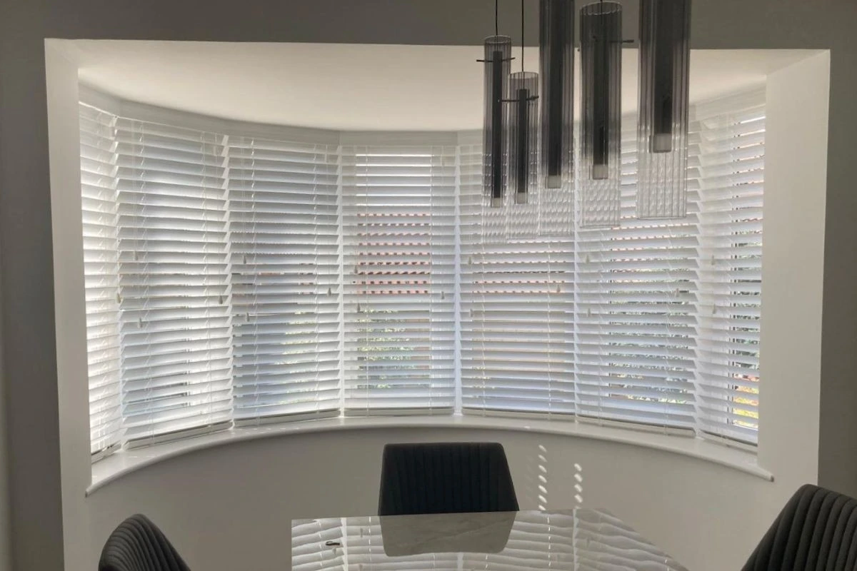 Fluid Stone Faux Wood Venetian blinds fitted in a bay window, creating soft light control in a modern dining space