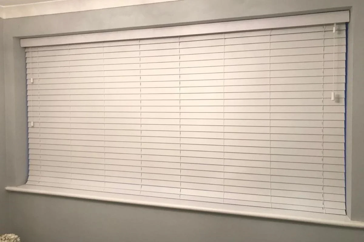 White faux wood Venetian blinds providing light and privacy control in a home office