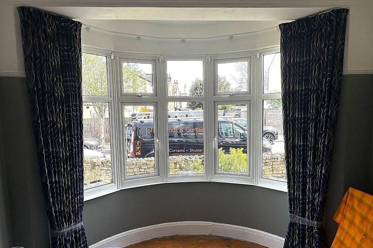 Pencil pleat curtains fitted to a bay window with a curved curtain track in a residential home