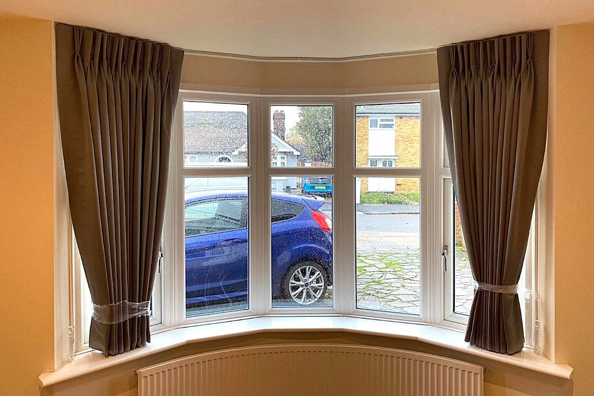 Pinch pleat curtains fitted to a bay window with tiebacks, providing a classic and tailored finish