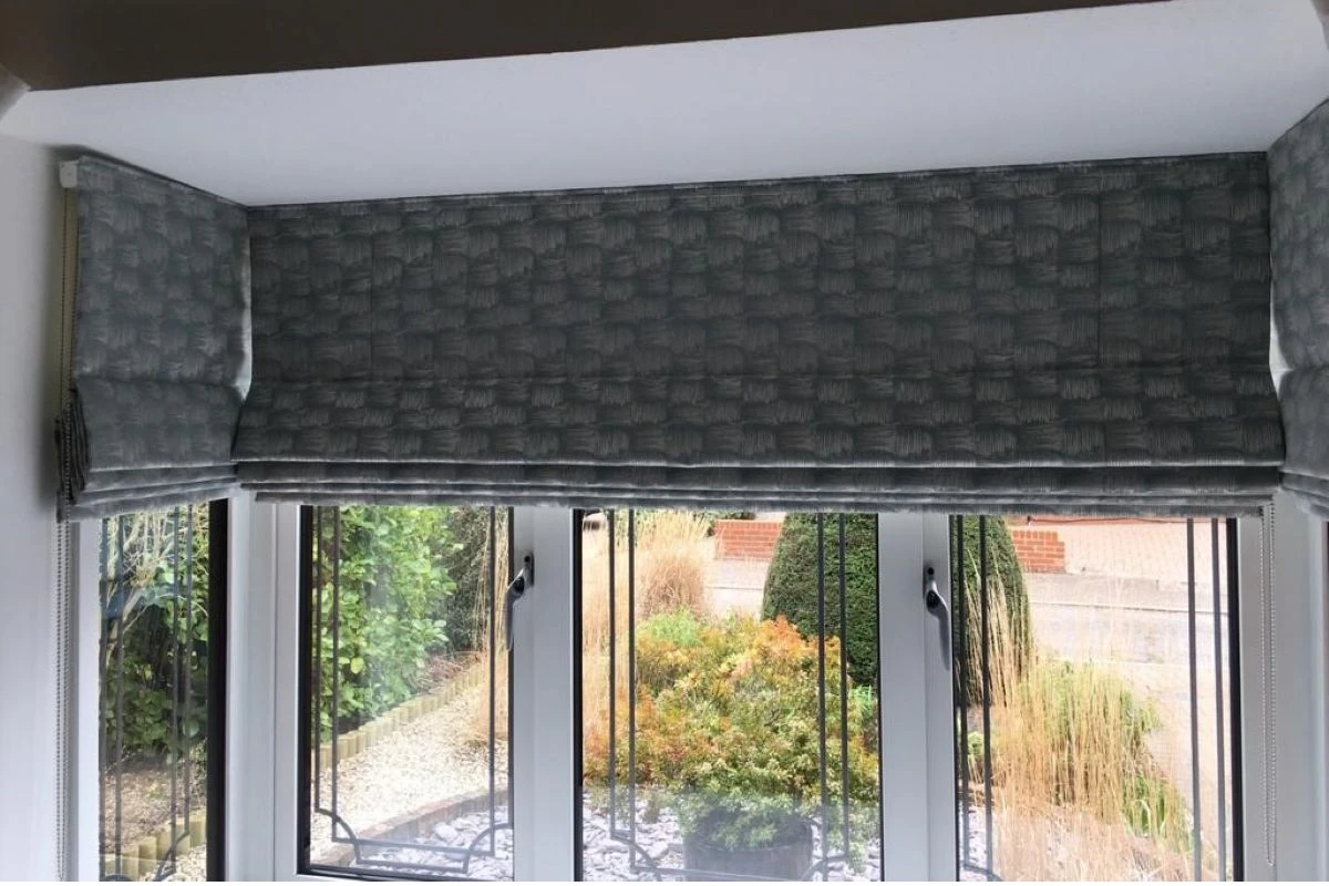 Roman blinds fitted into a 90 degree bay window with a neat, tailored finish