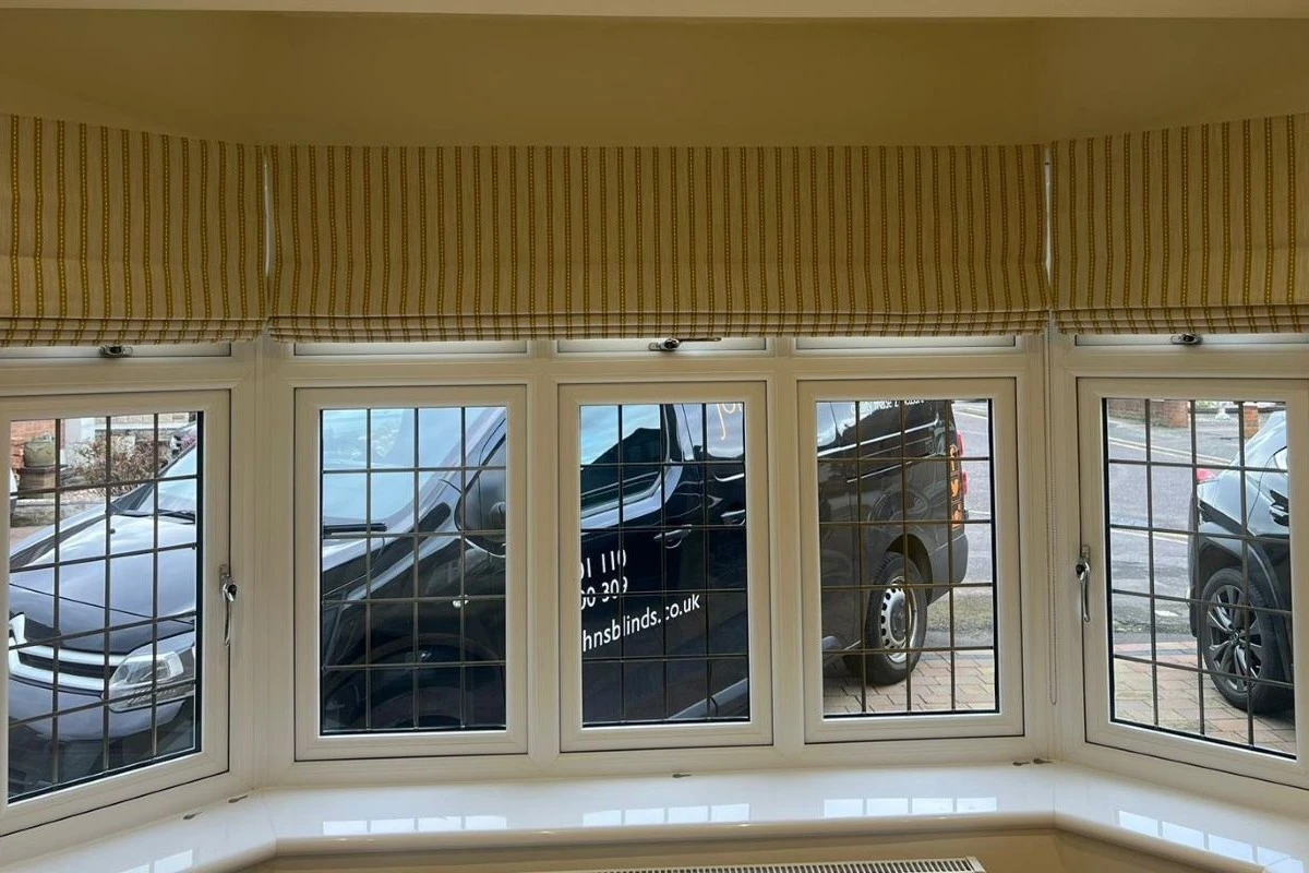 Roman blinds fitted across a bay window in a striped fabric