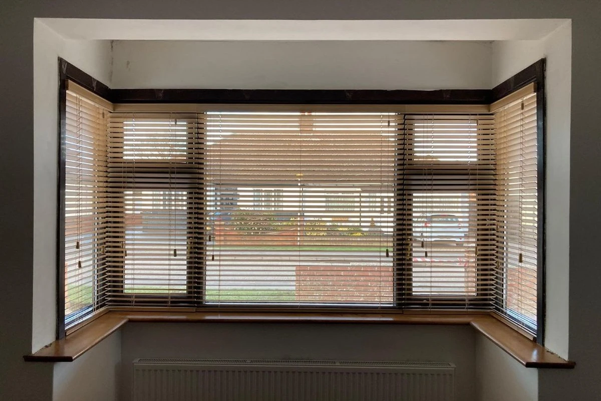 Wood Venetian blinds fitted in a square bay window, providing adjustable light control and privacy for a living space