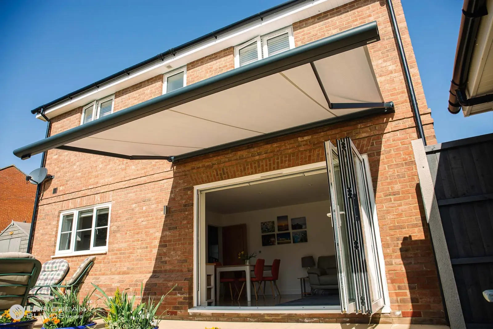 Tortola motorised patio awning in anthracite grey installed above bifold doors on brick home