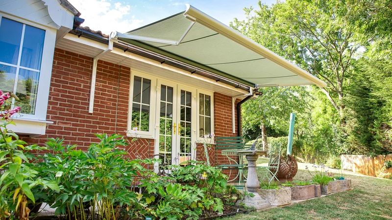 Anguilla patio awning installed on a red brick bungalow in Essex, providing shade over garden seating area