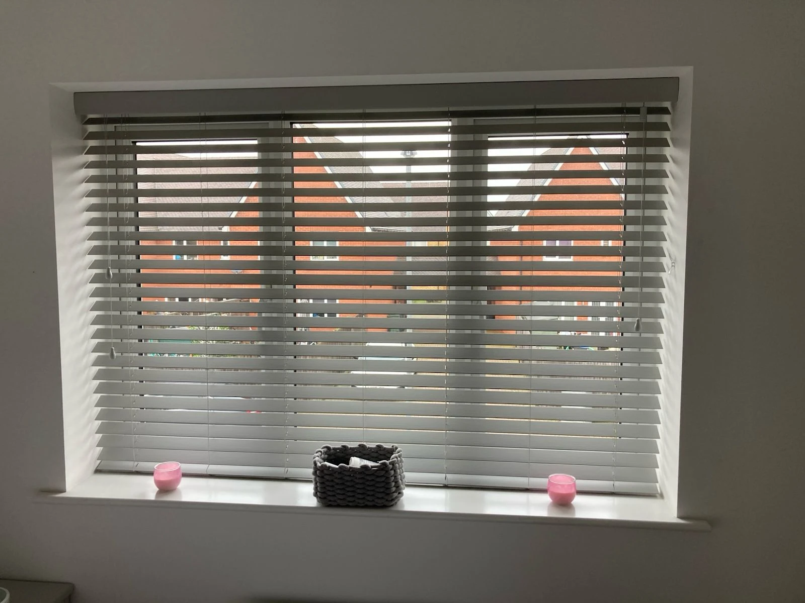 Grey faux wood Venetian blind fitted inside a recessed window, providing privacy and light control.