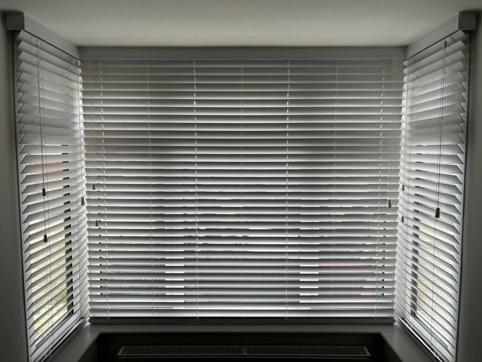 Grey PVC Venetian blinds fitted in a square bay window, offering privacy and adjustable light control.