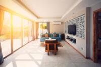 Bright sunlight entering a modern living room through large windows causing glare and heat build-up