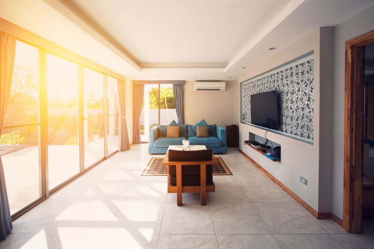 Bright sunlight entering a modern living room through large windows causing glare and heat build-up