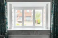 White plantation shutters controlling bright spring and summer daylight in a modern home