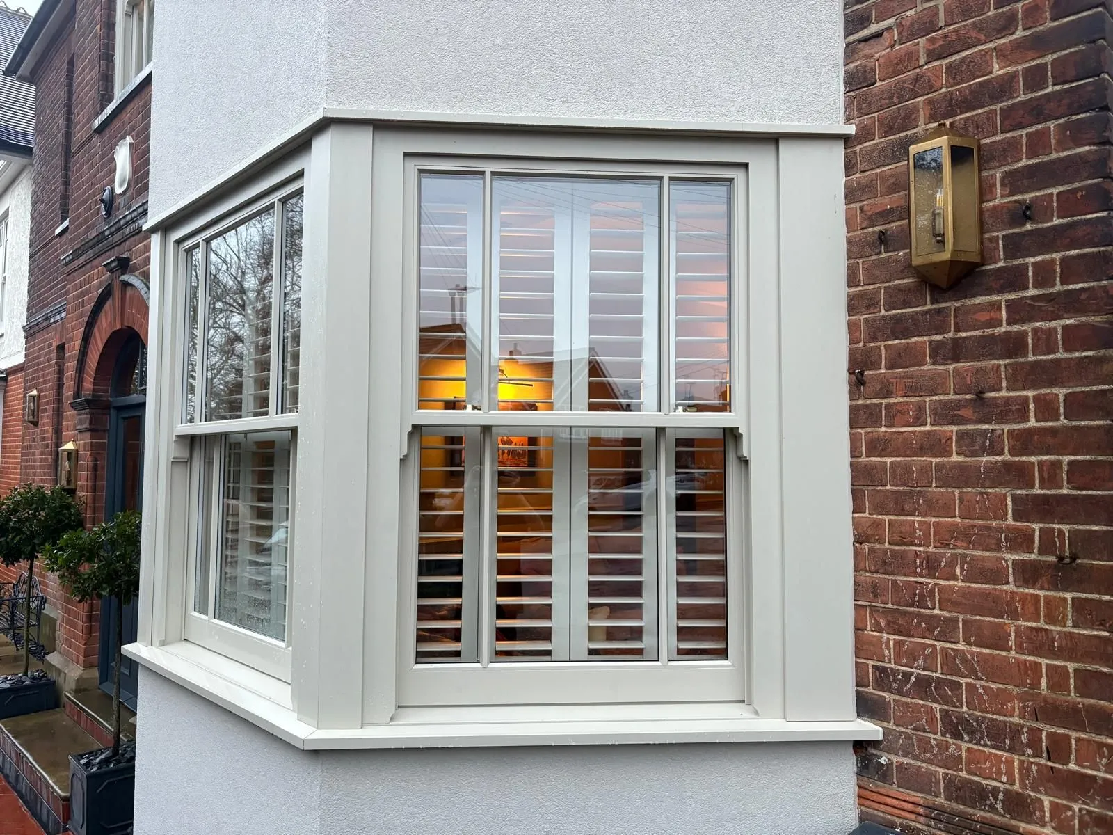 Full height plantation shutters fitted to a bay window, shown from outside to demonstrate a clean made-to-measure finish