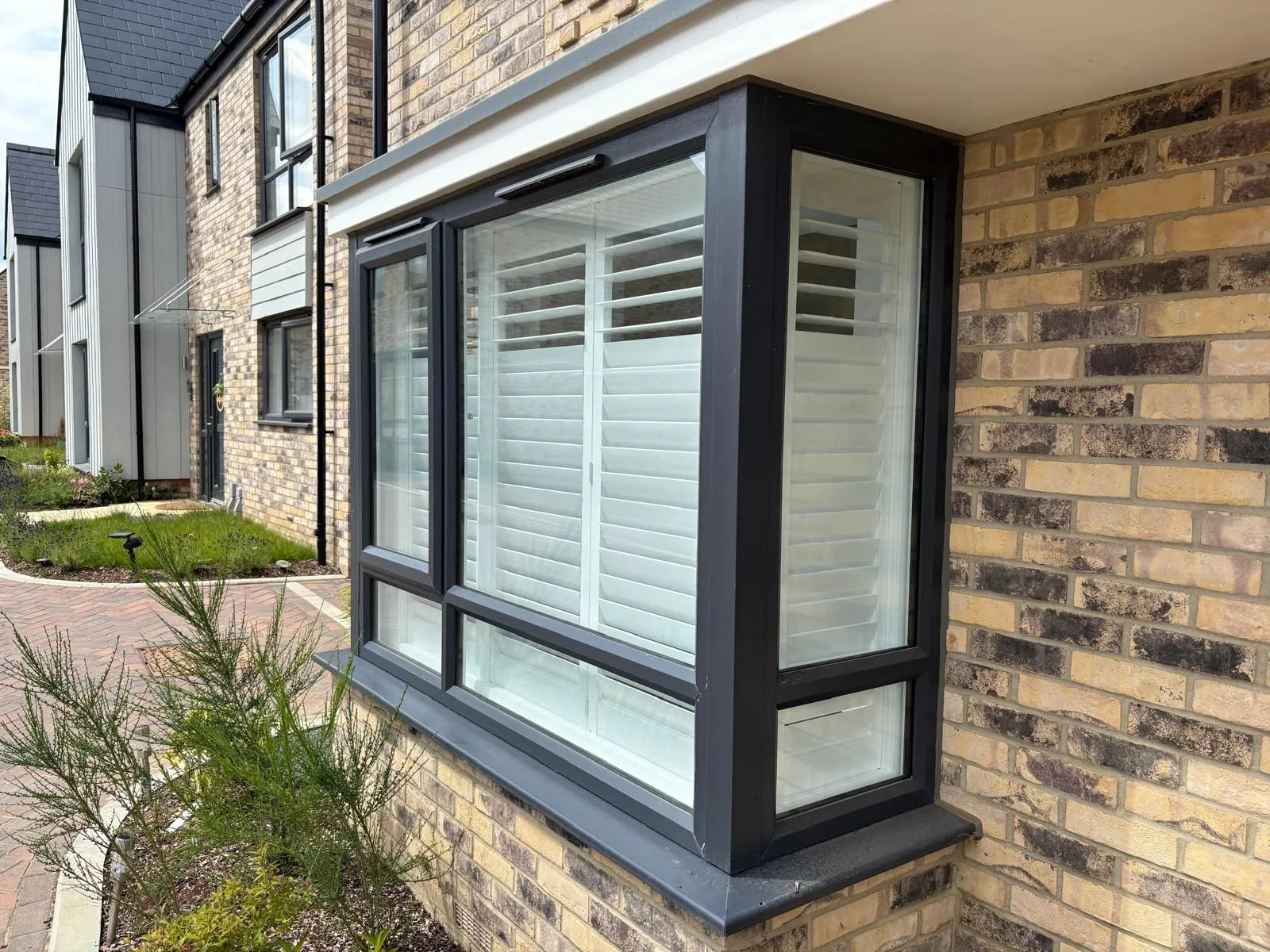Exterior view of plantation shutters fitted to a square bay window, showing a clean made-to-measure fit from outside the property