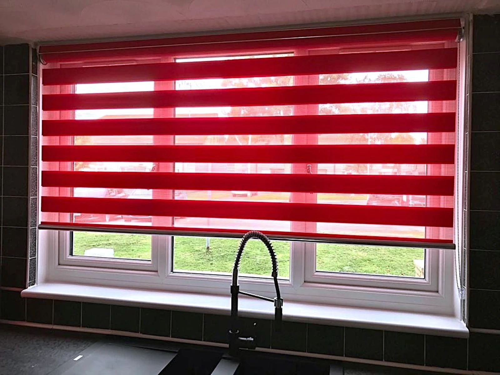 Add a Splash of Colour with Day & Night Blinds Red Day & Night blind installed in a contemporary kitchen window with layered light filtering fabric.