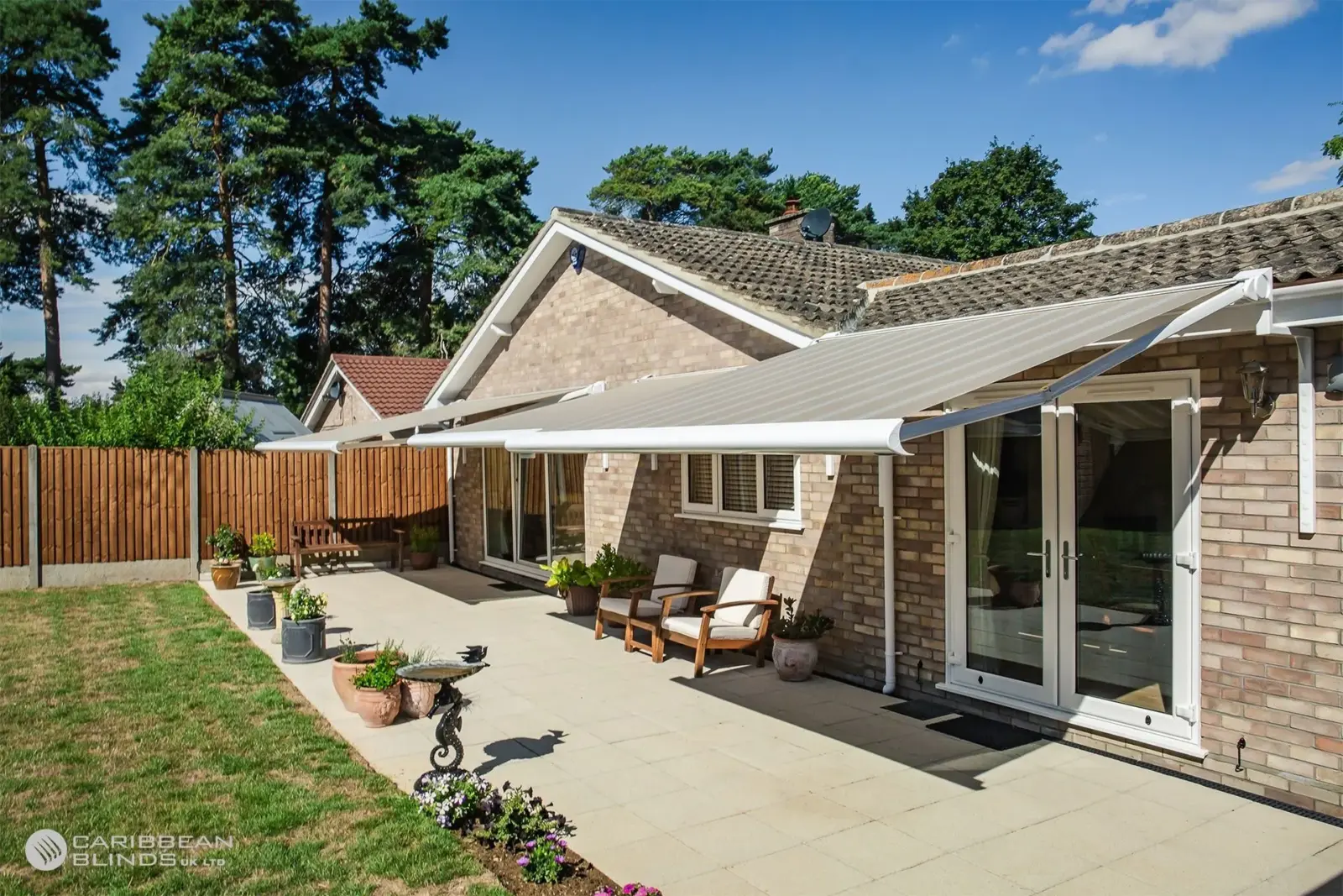 Full width retractable patio awning installed across rear patio of lovely home
