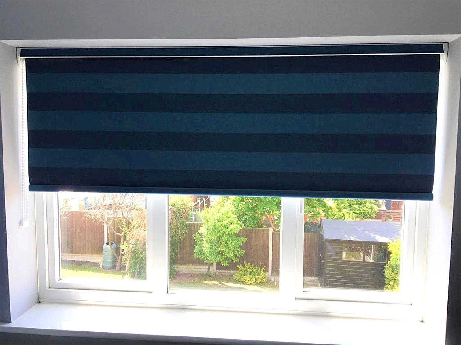 Dark blackout roller blind fitted within a modern bedroom window in an Essex home.