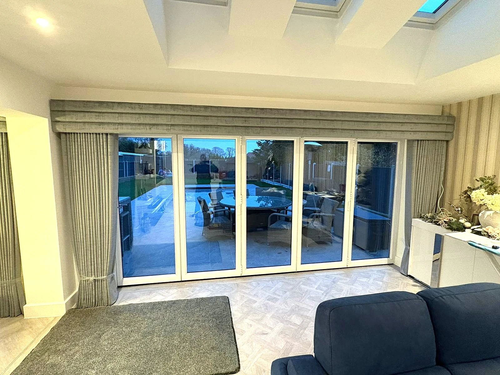 Grey made-to-measure curtains and pelmet installed over large bifold doors in a modern Essex living space.