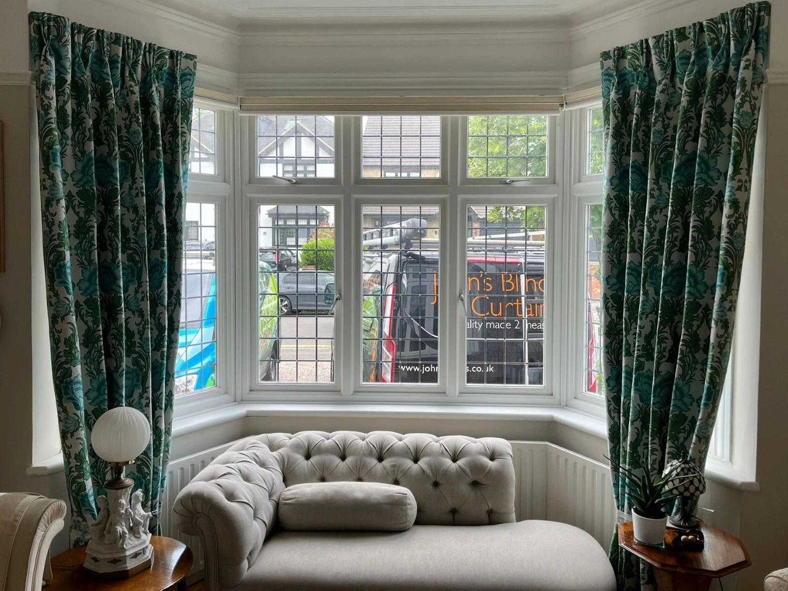 Green patterned made-to-measure curtains installed on a white bay window in a traditional living room.