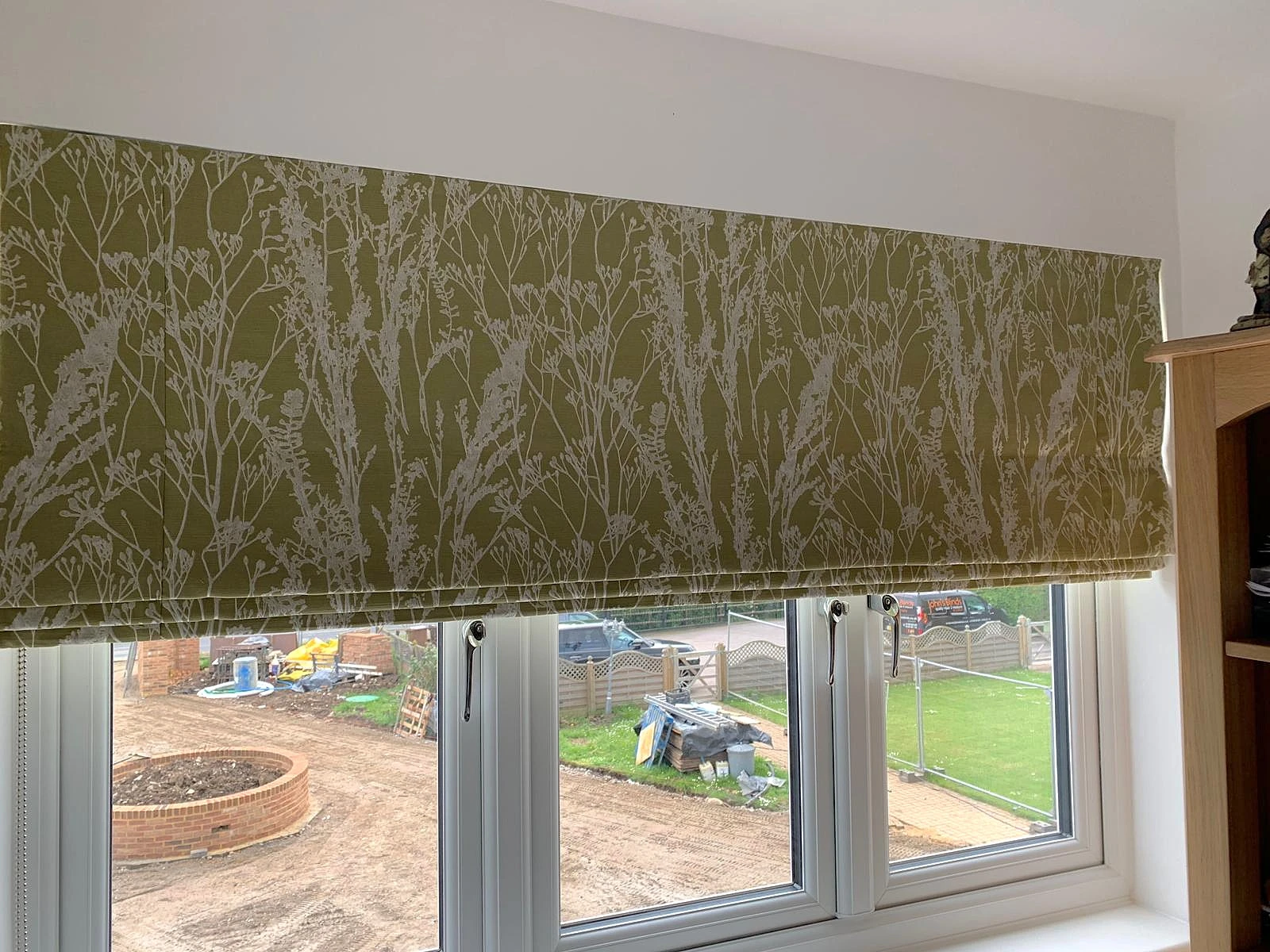 Green textured Roman blind fitted within a modern home interior.