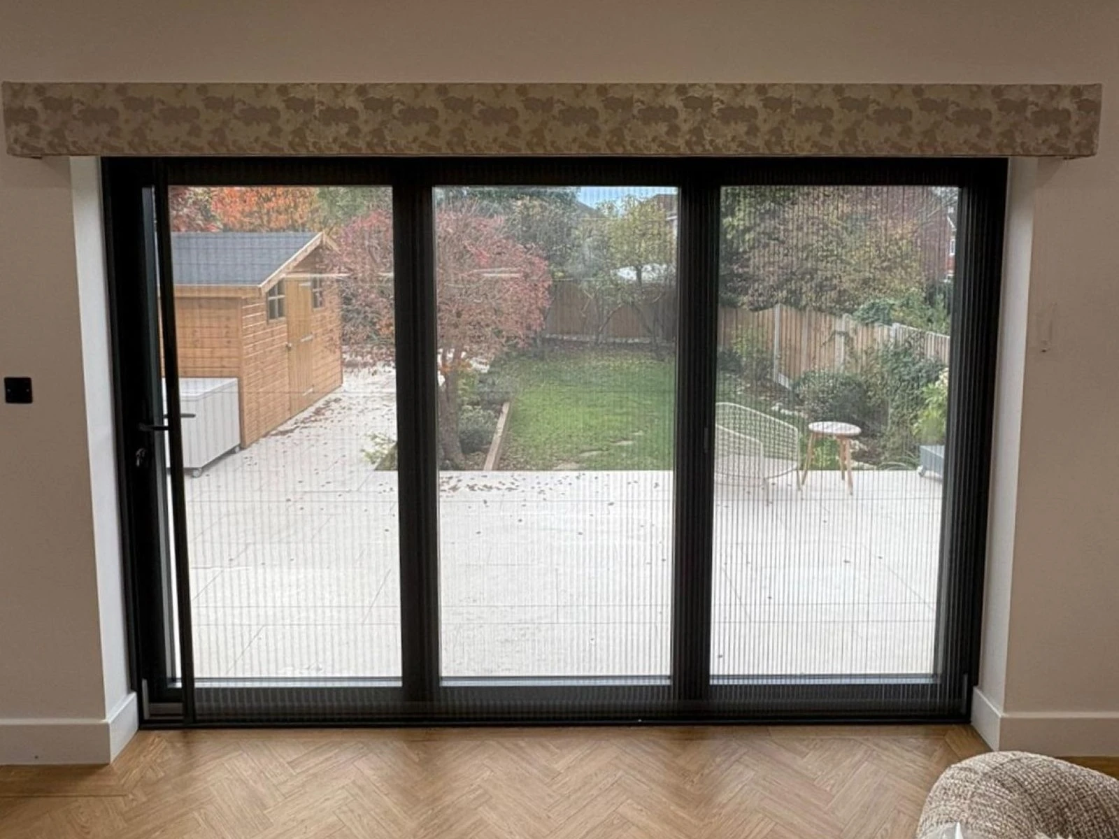 Black retractable fly screen fitted to large patio doors in a modern Essex home with discreet mesh design and unobstructed garden views.