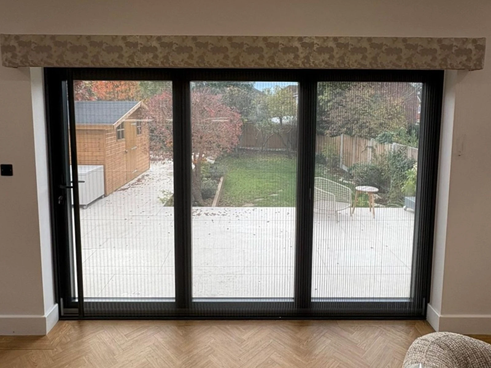 Integrated Fly Screen installed across black bifold doors in a modern Essex home allowing ventilation and insect protection