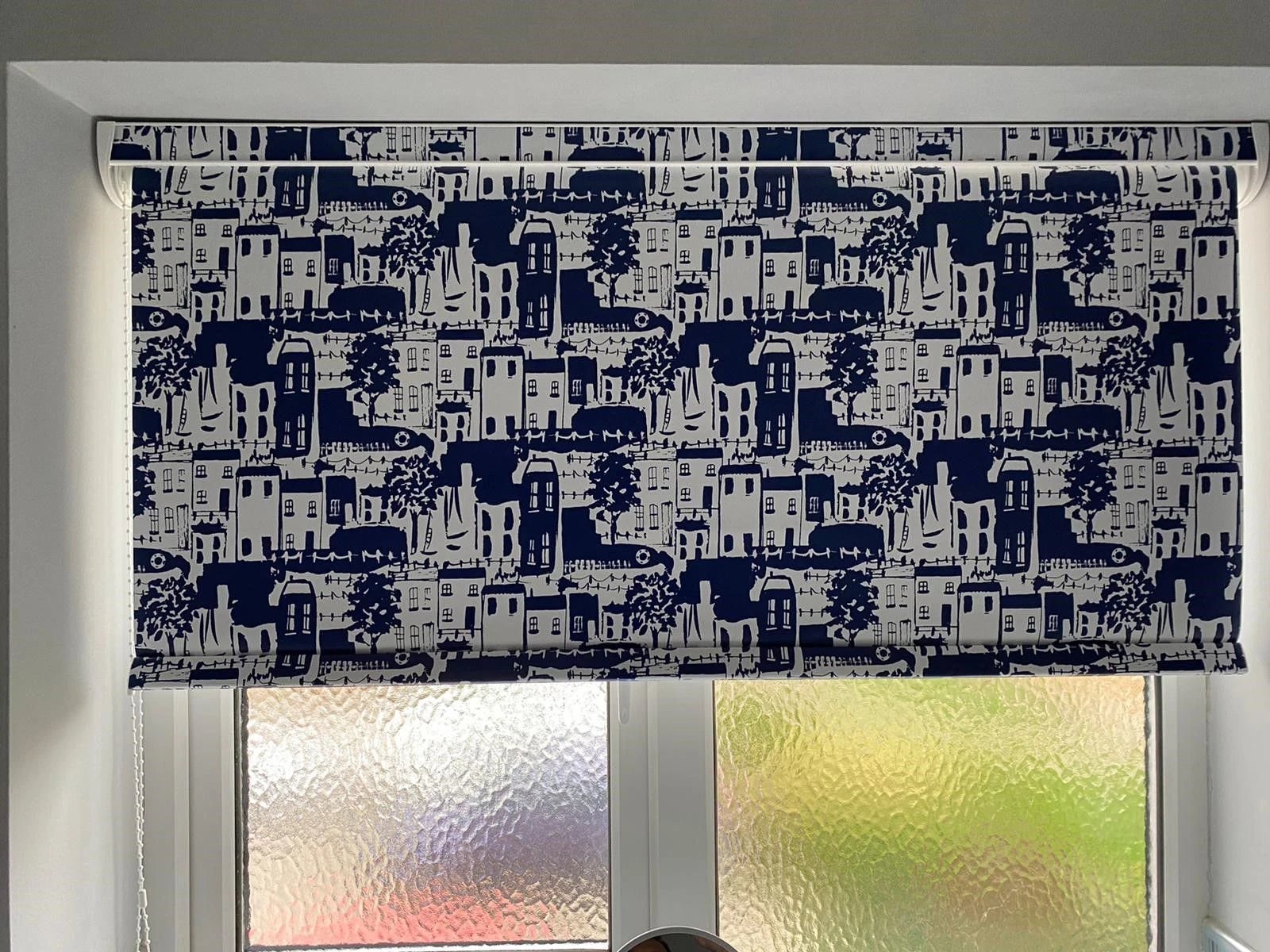Patterned waterproof PVC roller blind fitted within a bathroom window in an Essex home.