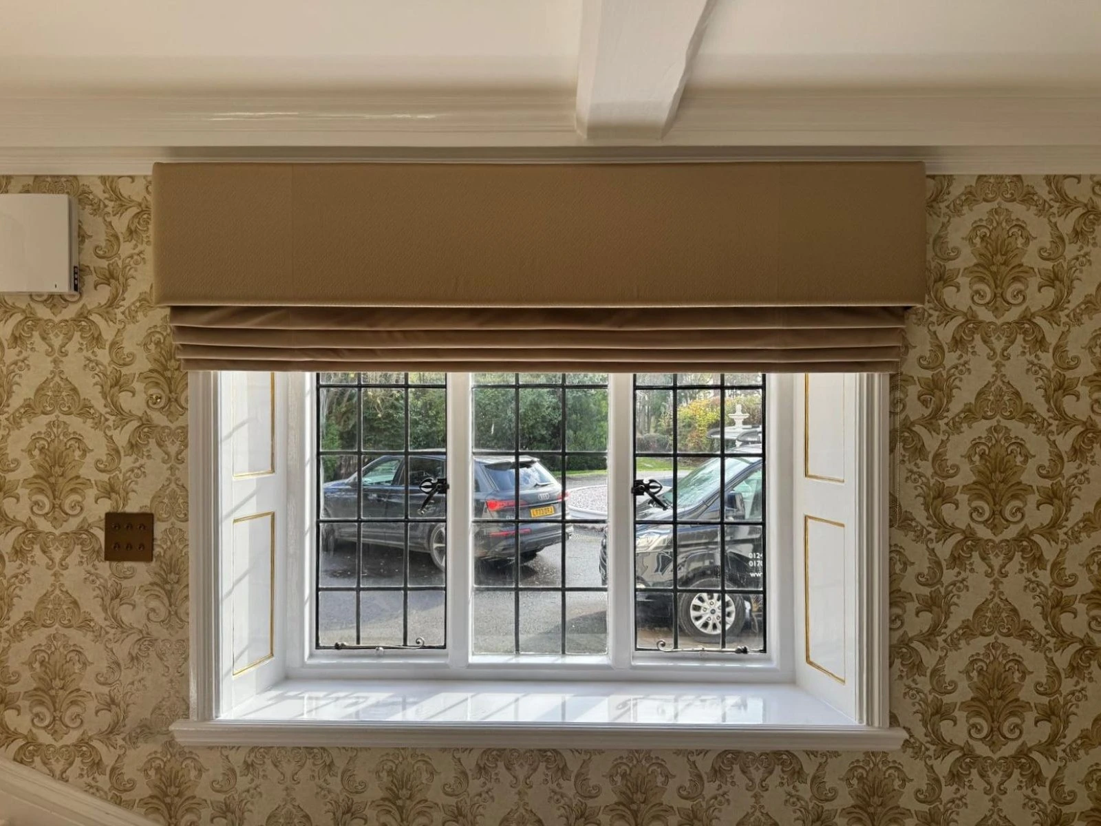 Neutral Roman blinds with matching pelmets fitted within a traditional styled living space.