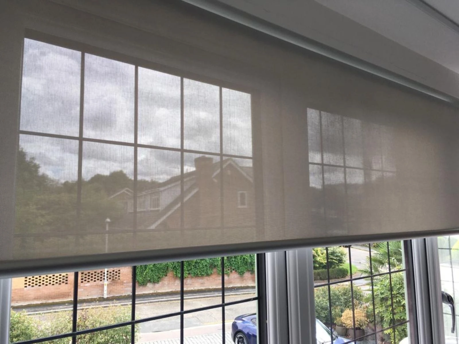 Sand colour screen roller blind fitted within a large modern window in an Essex home.