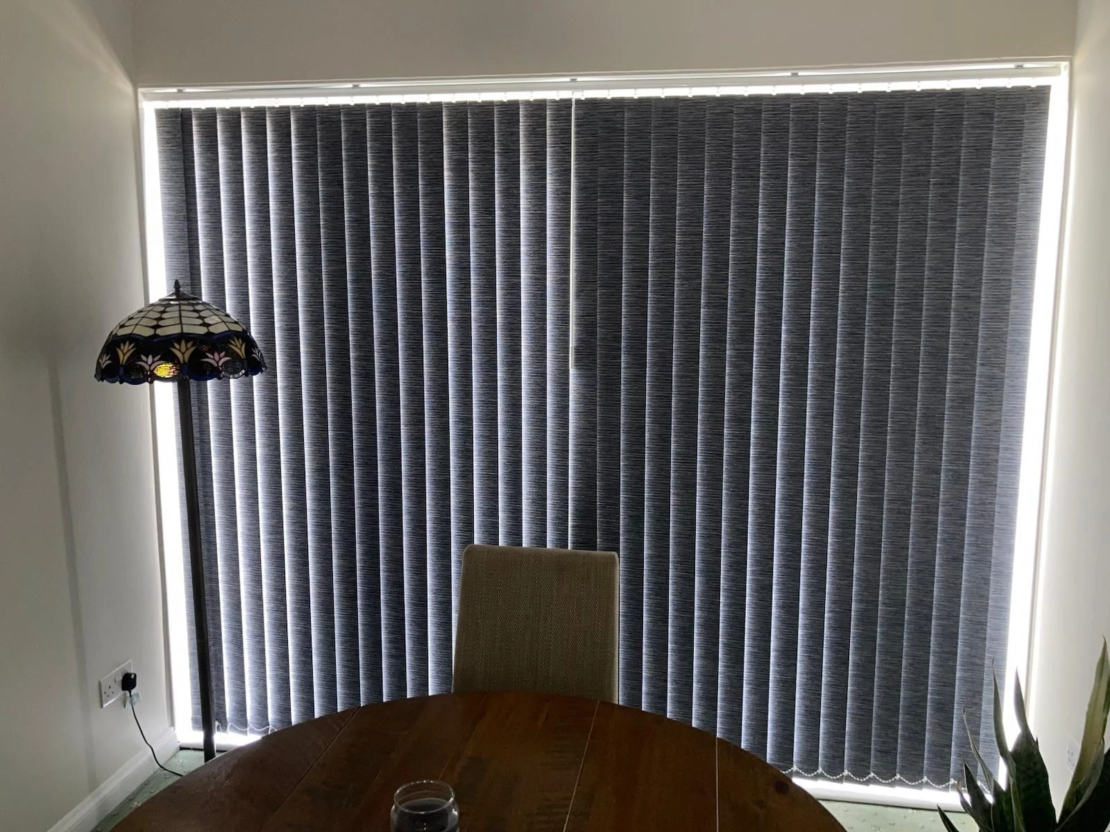 Dark grey vertical blinds with blackout fabric fitted to a large window in an Essex home, helping reduce light and improve privacy.
