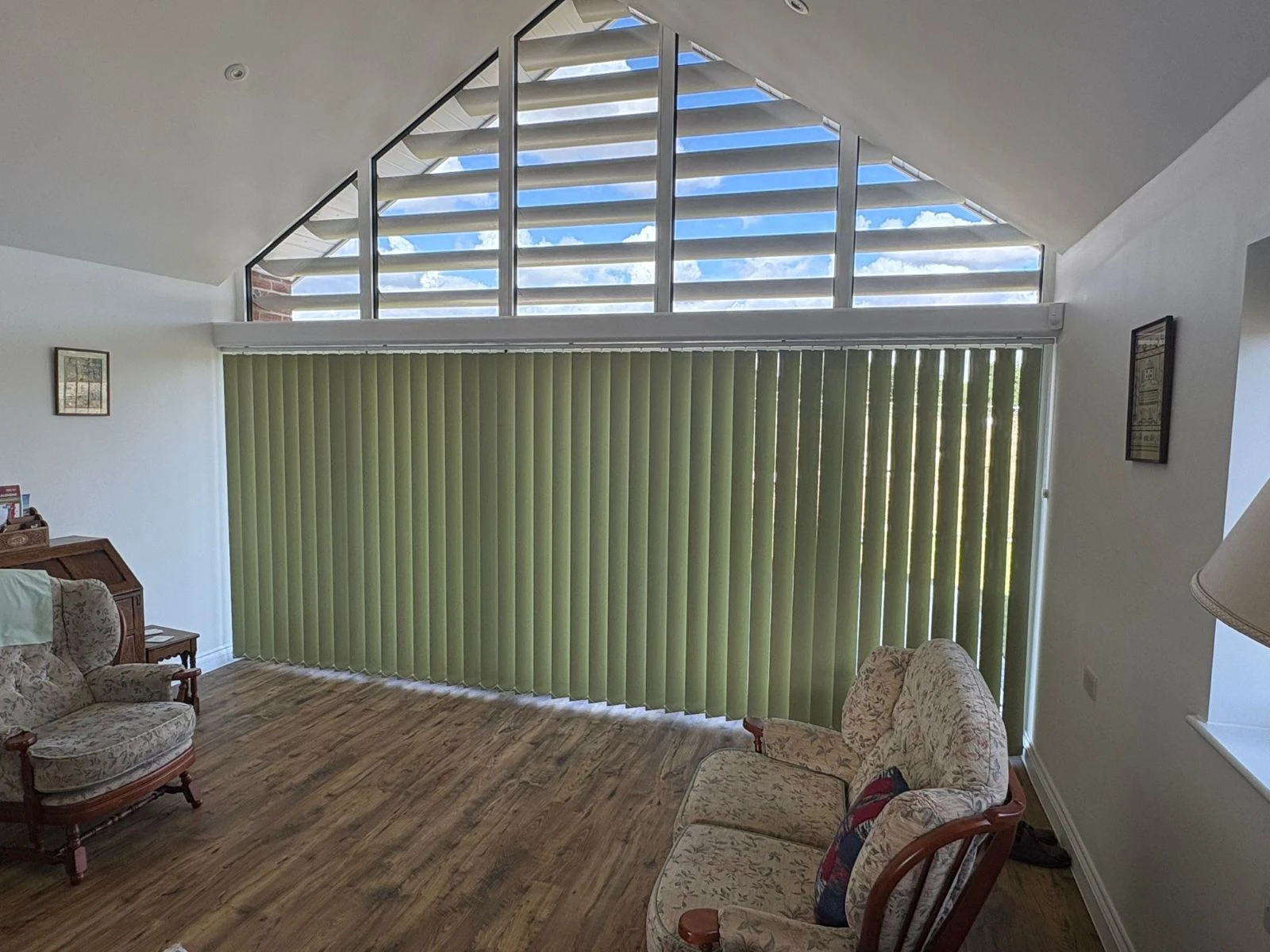 Green vertical blinds fitted across a large feature window in an Essex home, providing light control and privacy for a wide glazed living space.