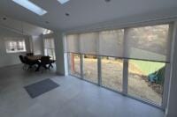 Screen fabric roller blinds filtering sunlight through large windows to reduce glare in a bright room