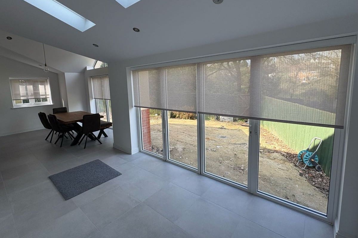 Screen fabric roller blinds filtering sunlight through large windows to reduce glare in a bright room