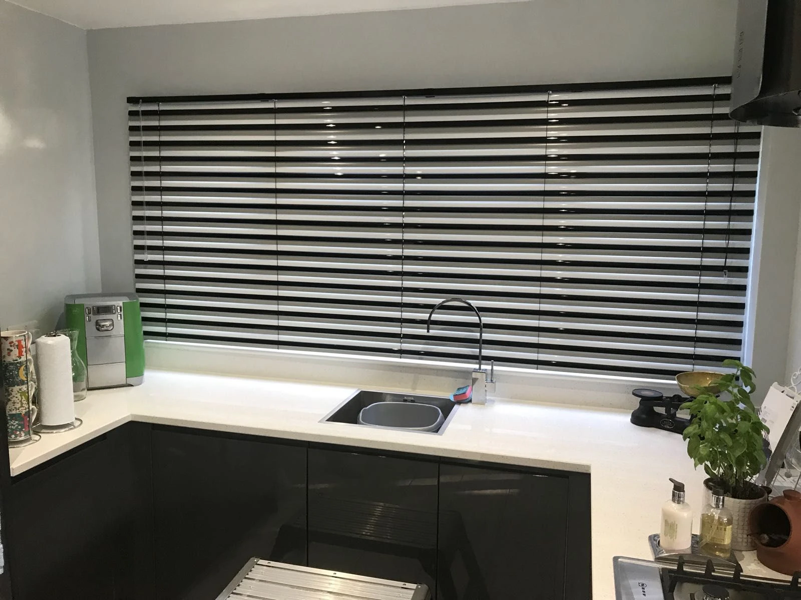 Black and silver Aluminium Venetian Blinds installed in a modern kitchen, providing adjustable light control and privacy.