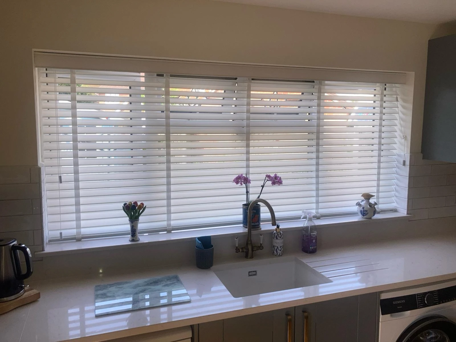 White Vela Fabric Venetian Blinds installed in a modern kitchen, providing adjustable privacy, soft light control and a contemporary window shading solution.